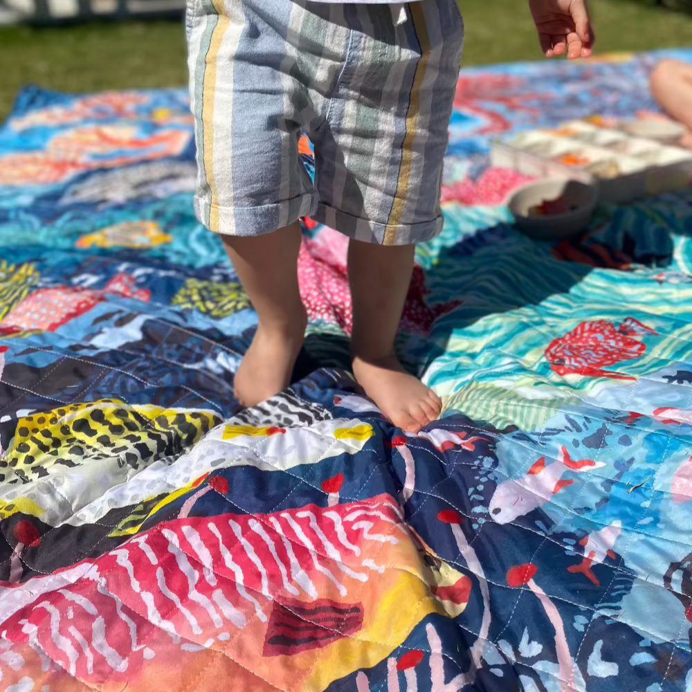 toddler playing in garden on a waterproof picnic blanket