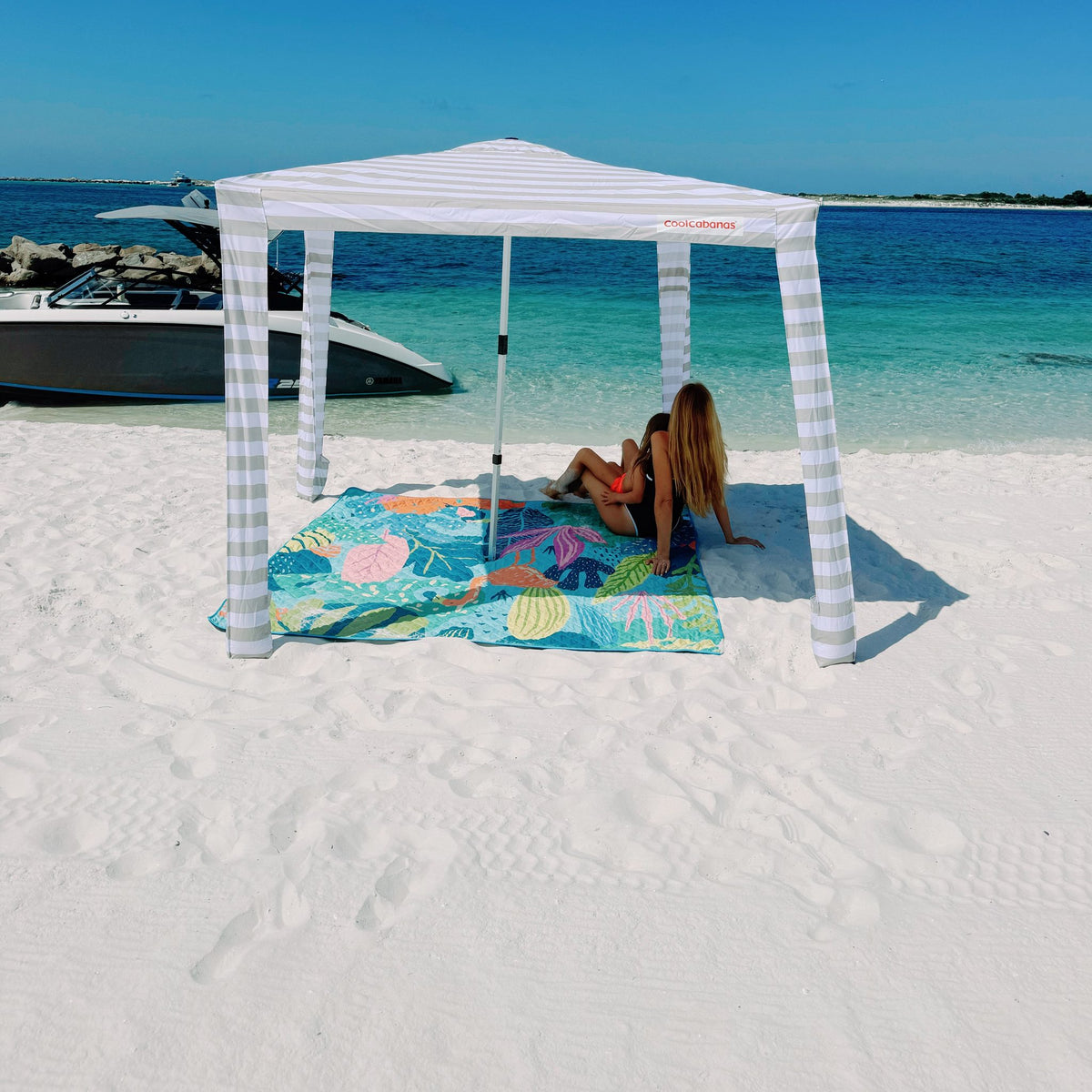 flamingo-a-go-go picnic blanket with umbrella hole under a beach cabana on white sand
