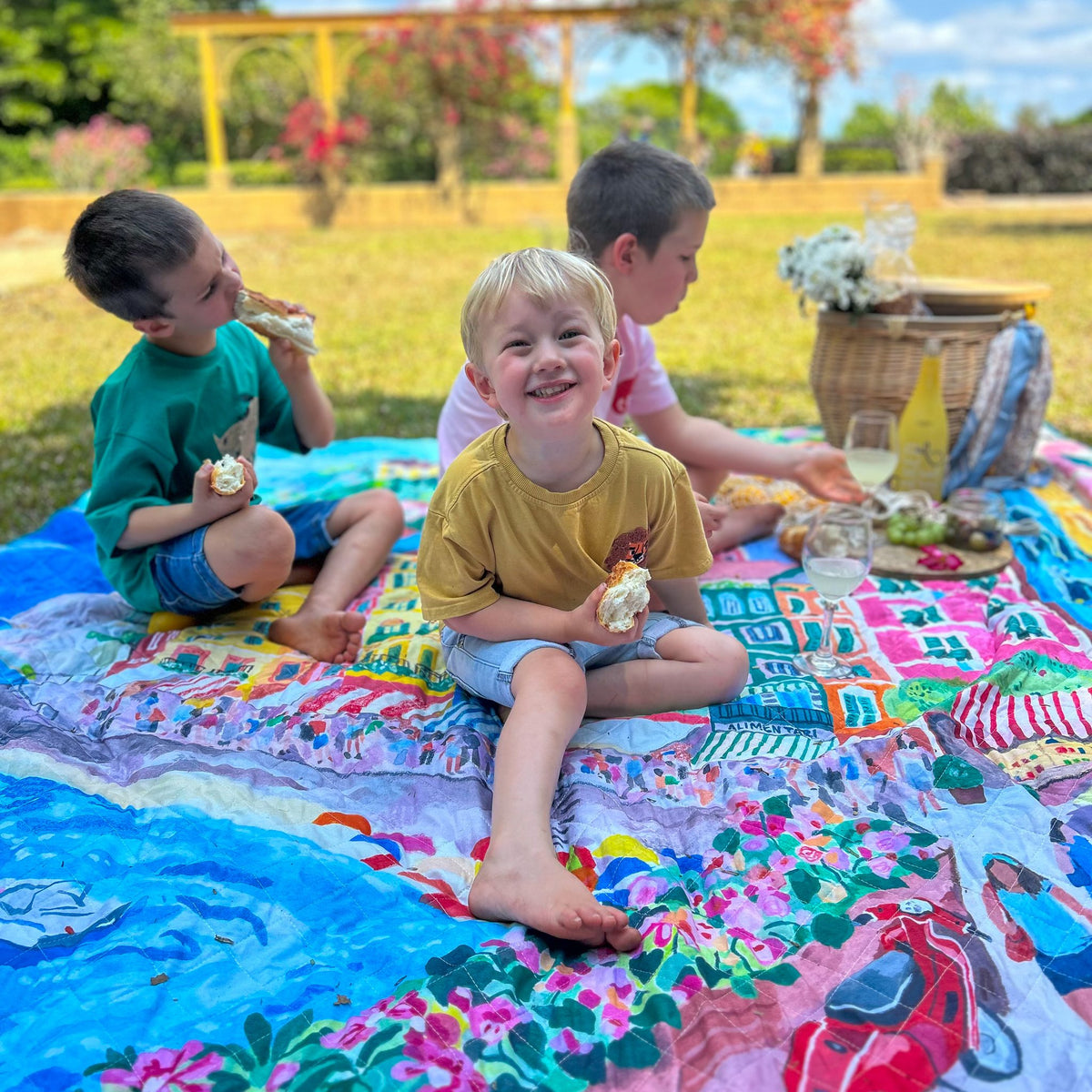 three children eating a picnic on the la dolce vita waterproof picnic blanket