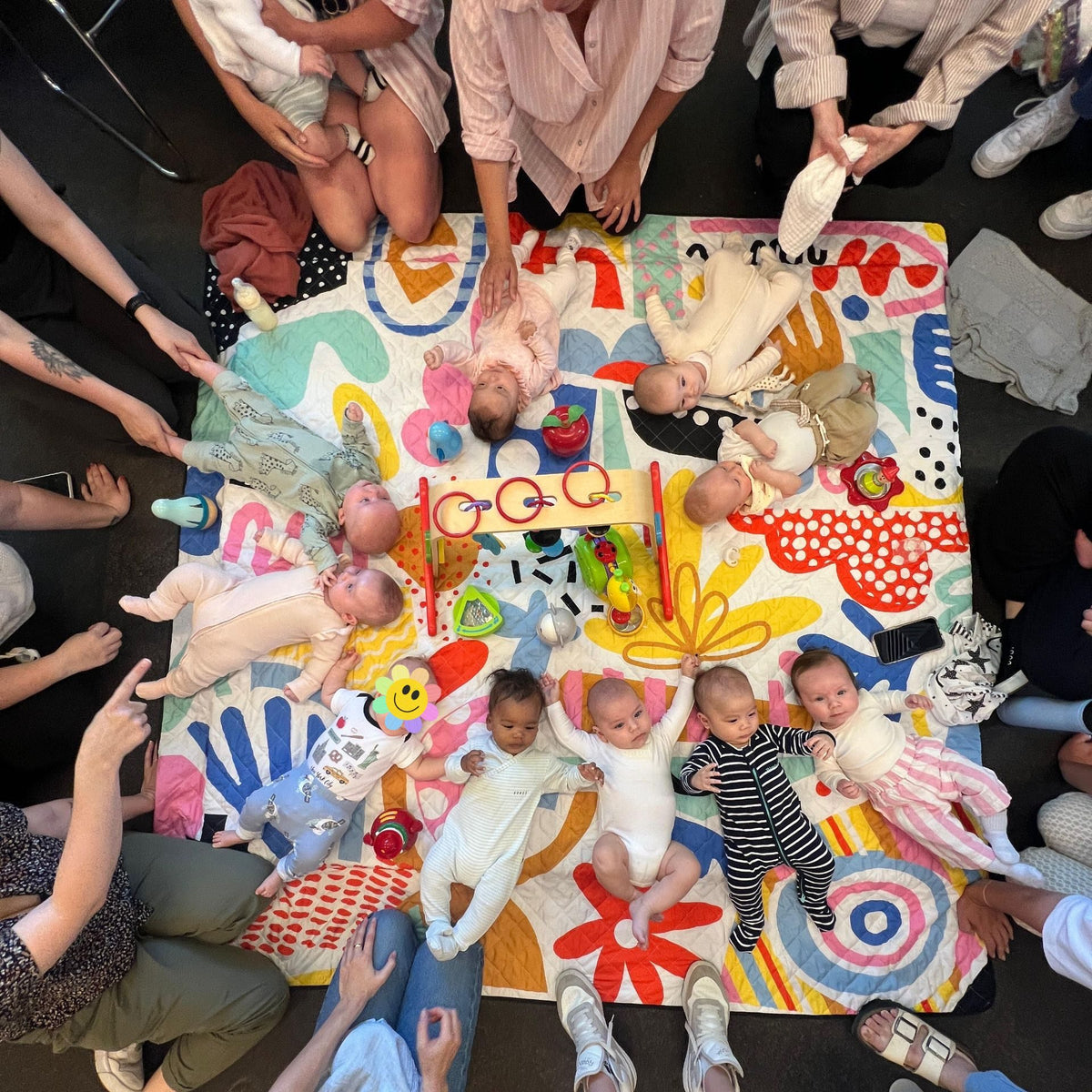 overhead view of a mothers group with babies lying on the pop pip pow waterproof picnic blanket