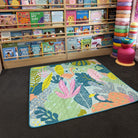 flamingo-a-go-go large waterproof playmat laid out in a bright playroom with bookshelves