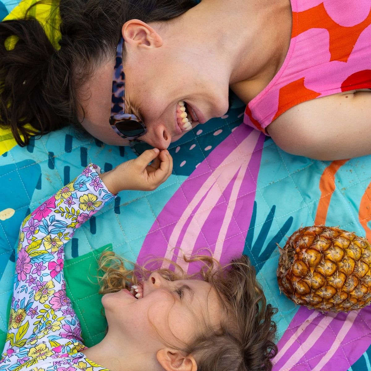 mother and daughter lying on the flamingo-a-go-go picnic blanket with umbrella hole