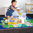child pouring water during messy play on the hola mamacita large waterproof playmat