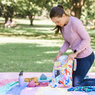 mother packing up a picnic into a pop pip pow wet bag in the park