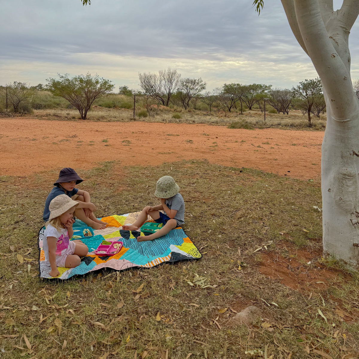 children having a picnic on the happy now large waterproof playmat under a gum tree in the outback