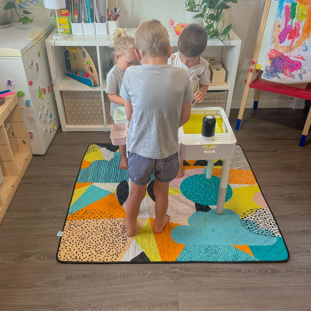 children painting at a table standing on the happy now large waterproof playmat
